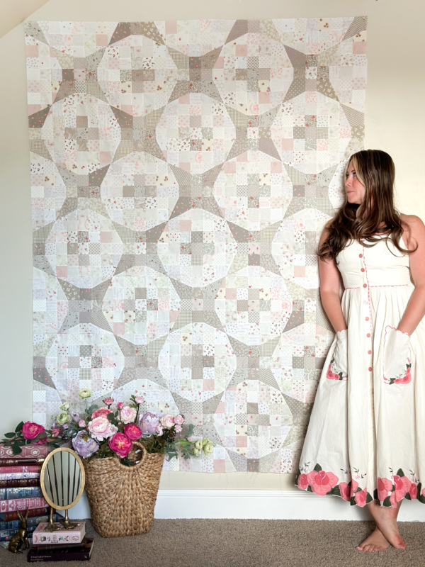 Girl standing in front of grey and white geometric quilt